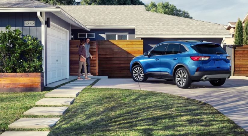 A blue 2022 Ford Escape 2022 Ford Escape vs 2022 Honda CR-V comparison.. shown in fron of a house from the rear at an angle after being involved in a