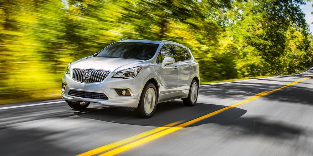 A silver 2018 Buick Envision is shown driving on an open road.