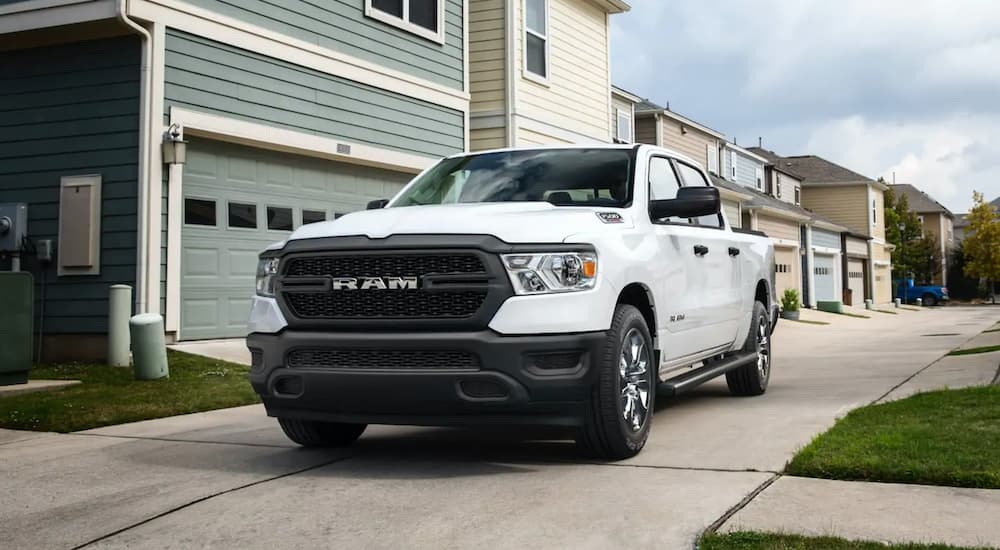 A white 2022 Ram 1500 is shown from the front at an angle parked in front of a house.
