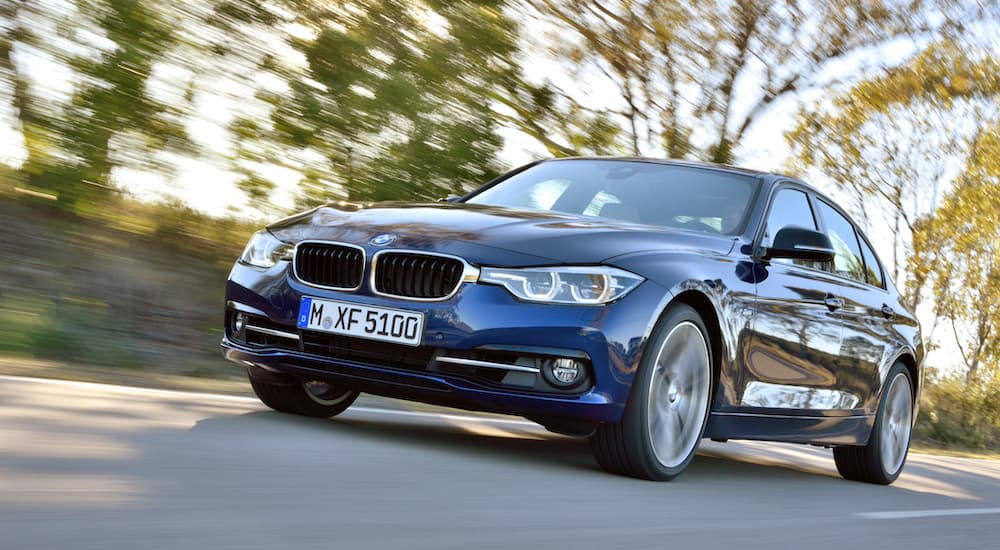 A blue 2015 BMW 3 Series is shown from the front driving on a street.