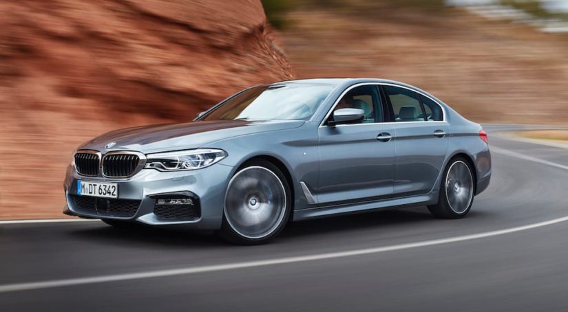 A silver 2017 BMW 5 Series is shown leaving a used BMW dealer near you.