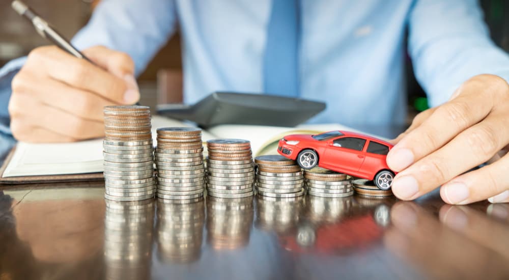 A toy car is shown driving up a stack of coins after searching how to 'value my car.'
