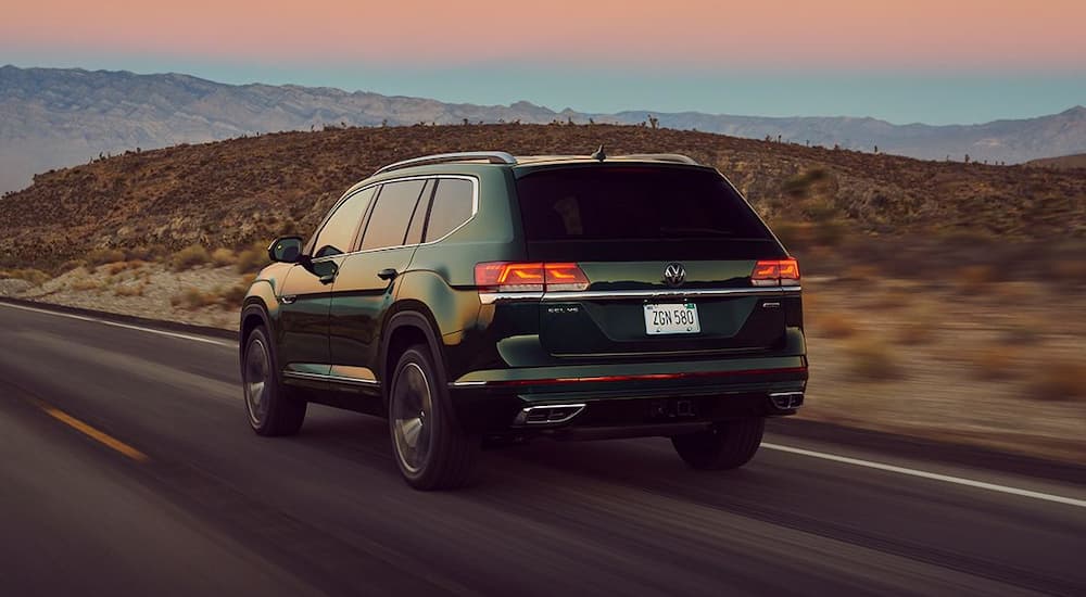 A green 2022 Volkswagen Atlas SEL is shown from the rear on a highway after leaving a Volkswagen dealer.