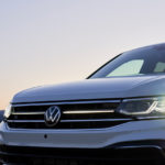 A close up of the grille and headlight of on a white 2022 Volkswagen Tiguan is shown during a sunset.