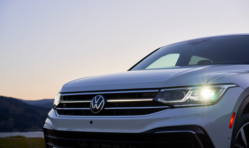 A close up of the grille and headlight of on a white 2022 Volkswagen Tiguan is shown during a sunset.