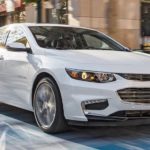 A white 2016 Chevy Malibu is shown on a city street after leaving an Allentown used car dealer.