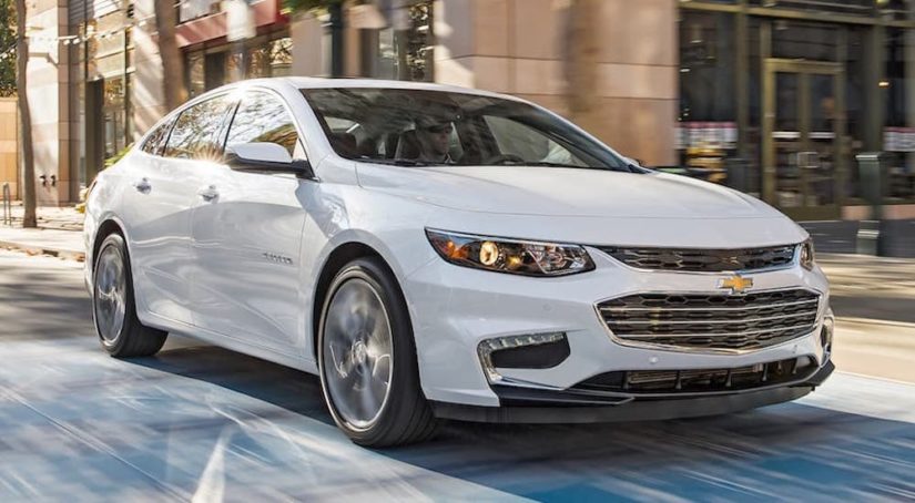 A white 2016 Chevy Malibu is shown on a city street after leaving an Allentown used car dealer.