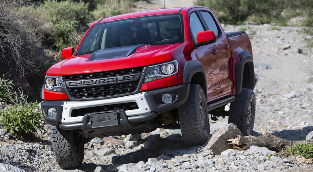 A red 2022 Chevy Colorado ZR2 Bison is shown from the front crawling over some rocks.
