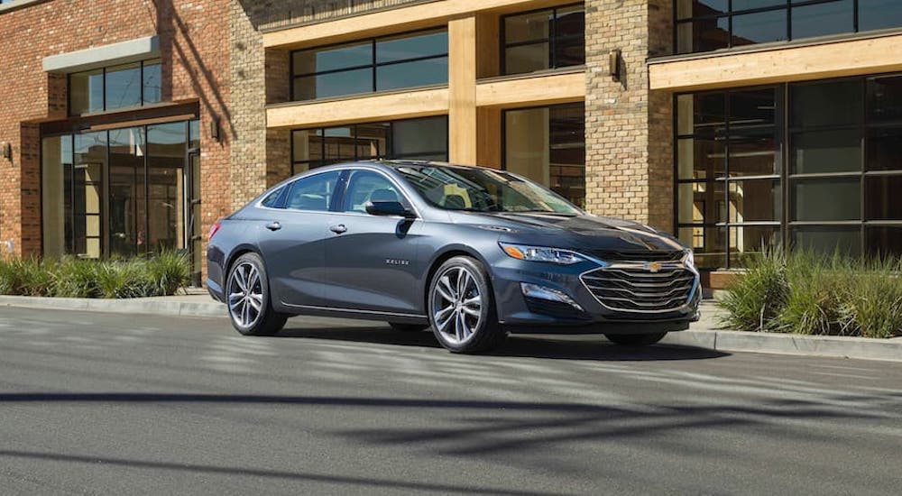 A grey 2019 Chevy Malibu is shown from the front at an angle on a city street.