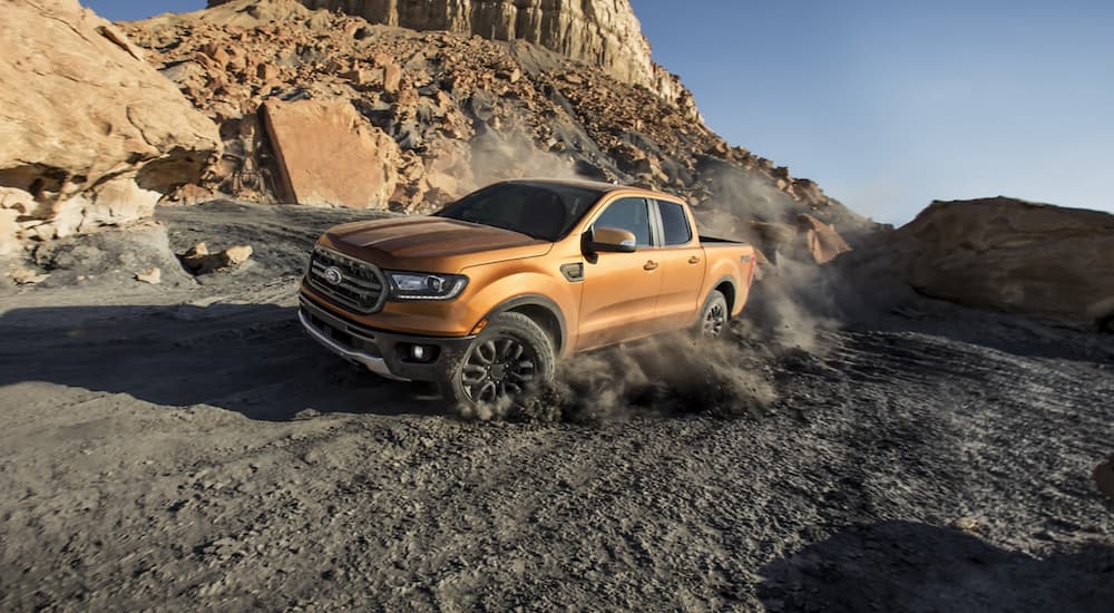 A gold 2022 Ford Ranger FX4 is shown from the front at an angle driving through a rocky desert.