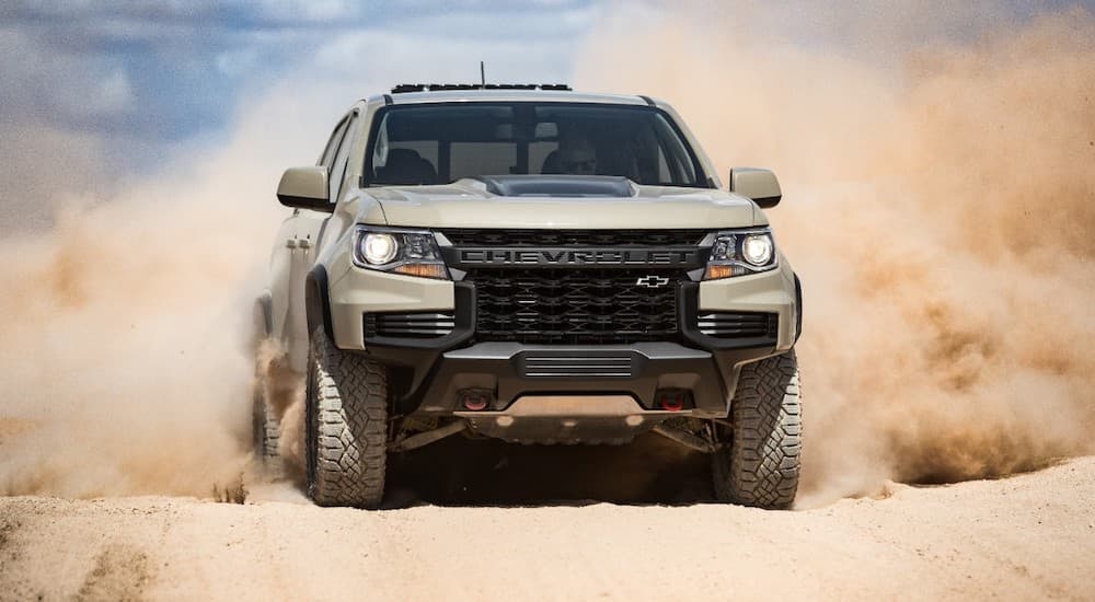 A tan 2022 Chevy Colorado ZR2 is shown from the front as it drives through sand.