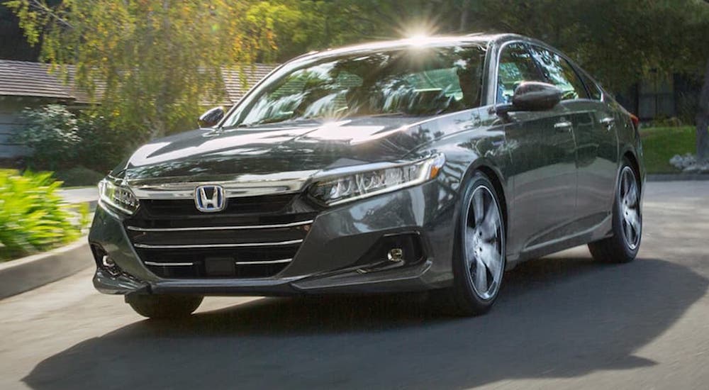 A grey 2021 Honda Accord Hybrid is shown from the front driving in a suburban area.