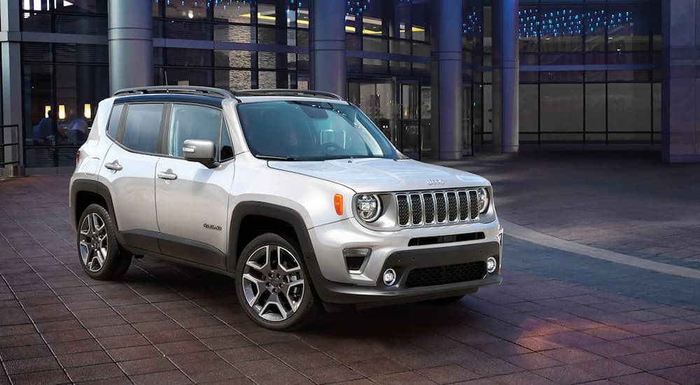 A silver 2022 Jeep Renegade Limited is shown parked outside of a glass building.