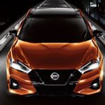 An orange 2021 Nissan Maxima is shown from the front on a dark road.