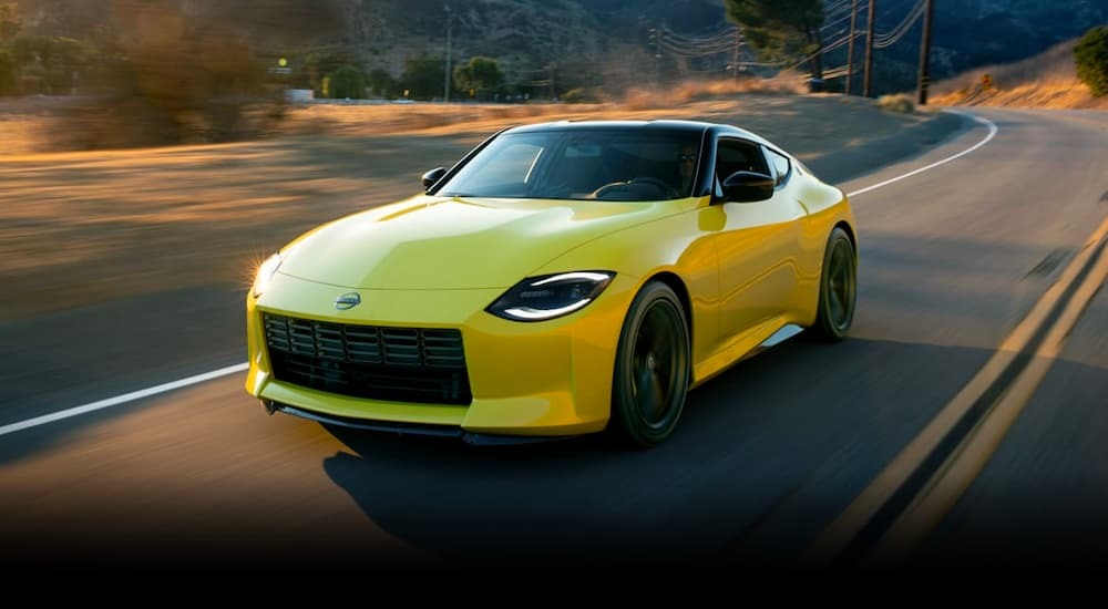 A yellow 2023 Nissan Z is shown from the front at an angle while it drives down the road.