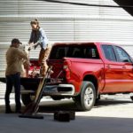 Two people are shown loading supplies into the bed of a red 2022 Chevy Silverado Limited.