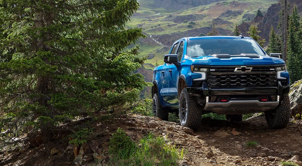 A blue 2022 Chevy Silverado 1500 ZR2 is shown driving on a forest trail.