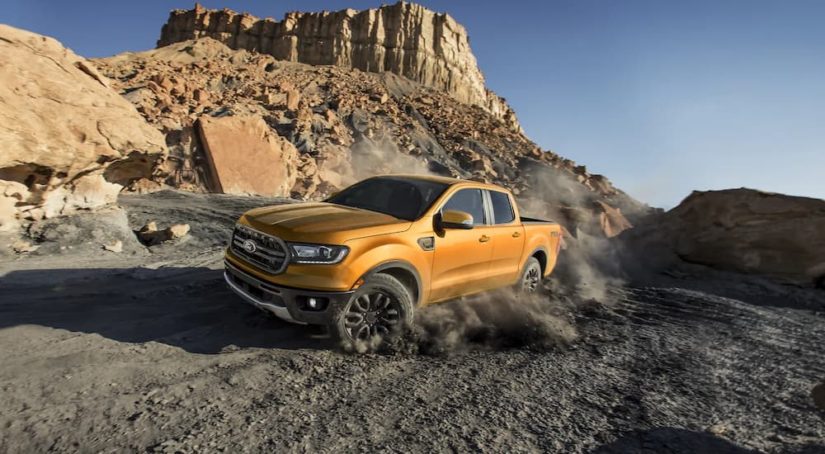 An orange 2022 Ford Ranger FX4 is shown off-roading on a dusty trail.