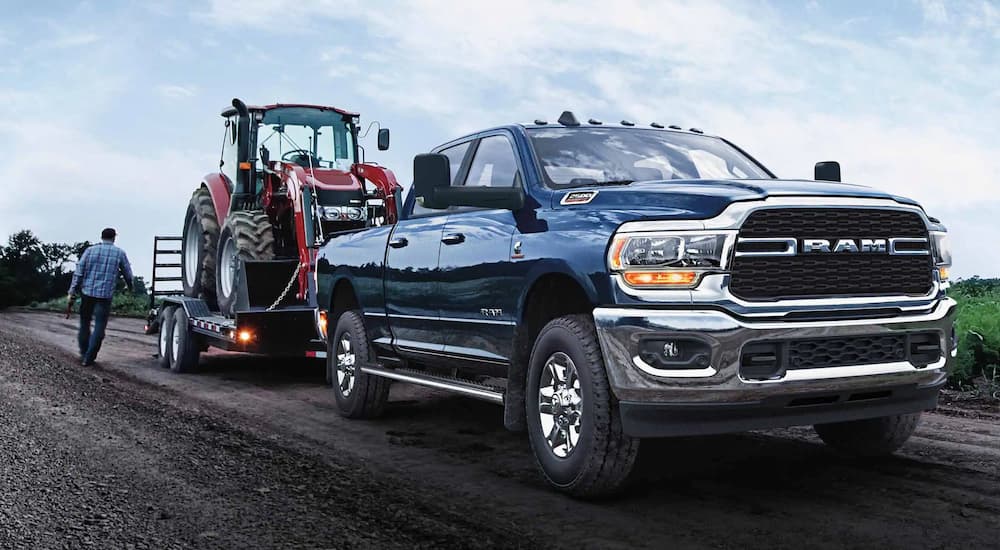 A blue 2022 Ram 2500 is shown towing heavy machinery. 