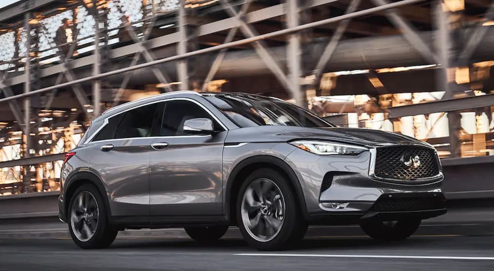 A silver 2022 Infiniti QX50 is shown driving on a city road.
