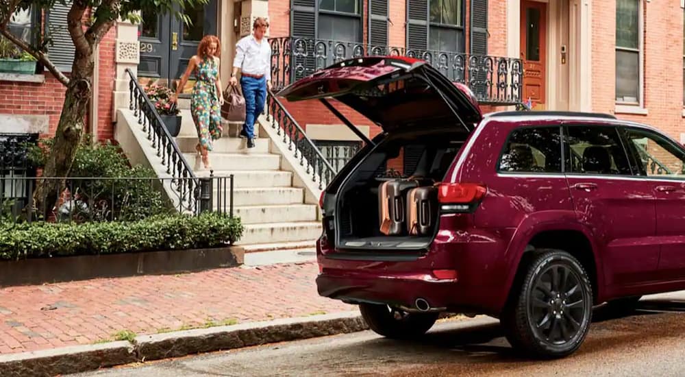 A red 2022 Jeep Grand Cherokee WK is shown with the lift gate open on a city street.