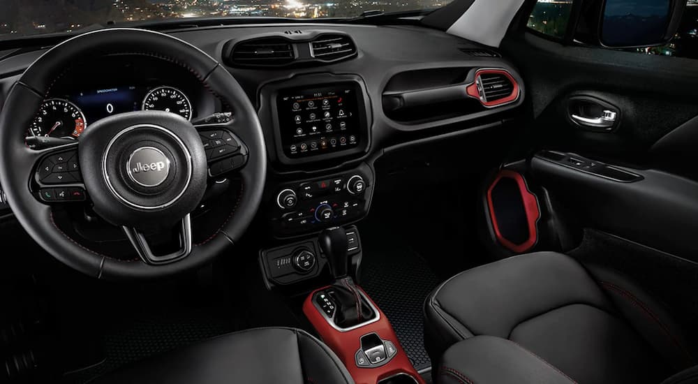 The black and red interior of a 2022 Jeep Renegade shows the steering wheel and center console.