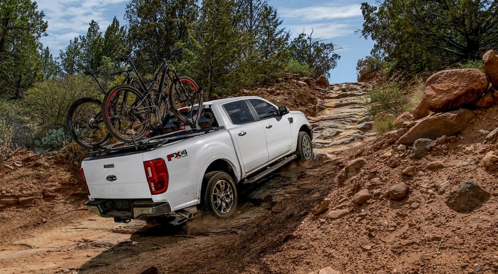 A white 2022 Ford Ranger Lariat is shown driving up a steep rocky trail.