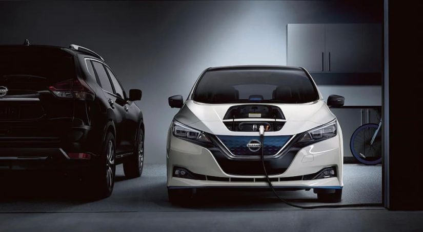 A white 2022 Nissan Leaf is shown charging in a garage.
