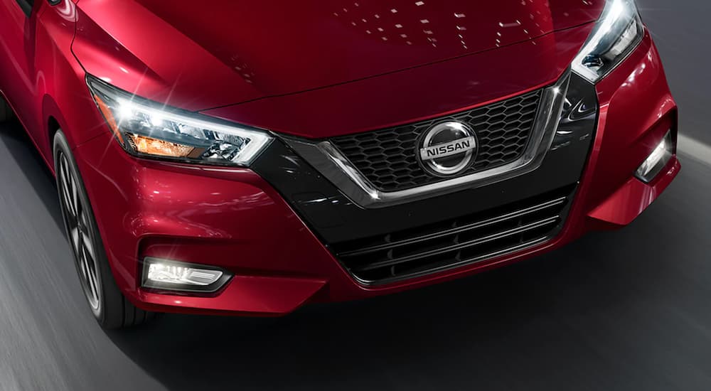 A close up of the front of a 2022 Nissan Versa is shown while driving on a highway.