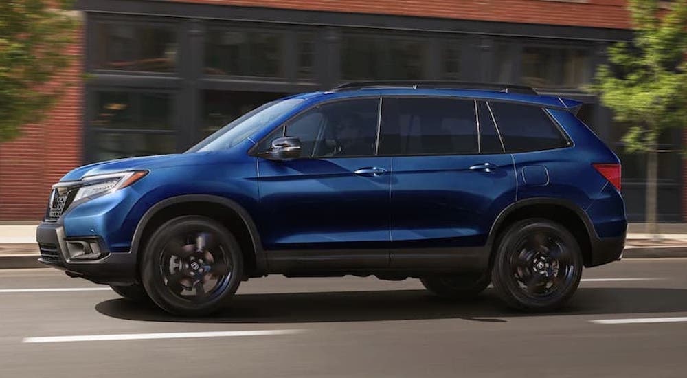 A blue 2022 Honda Passport is shown from the side as it drives down the road.