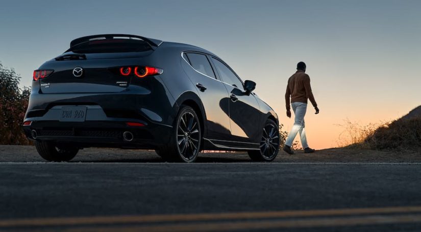 A black 2022 Mazda 3 Turbo Hatchback is shown from the rear at an angle at dusk after leaving a Mazda dealer.