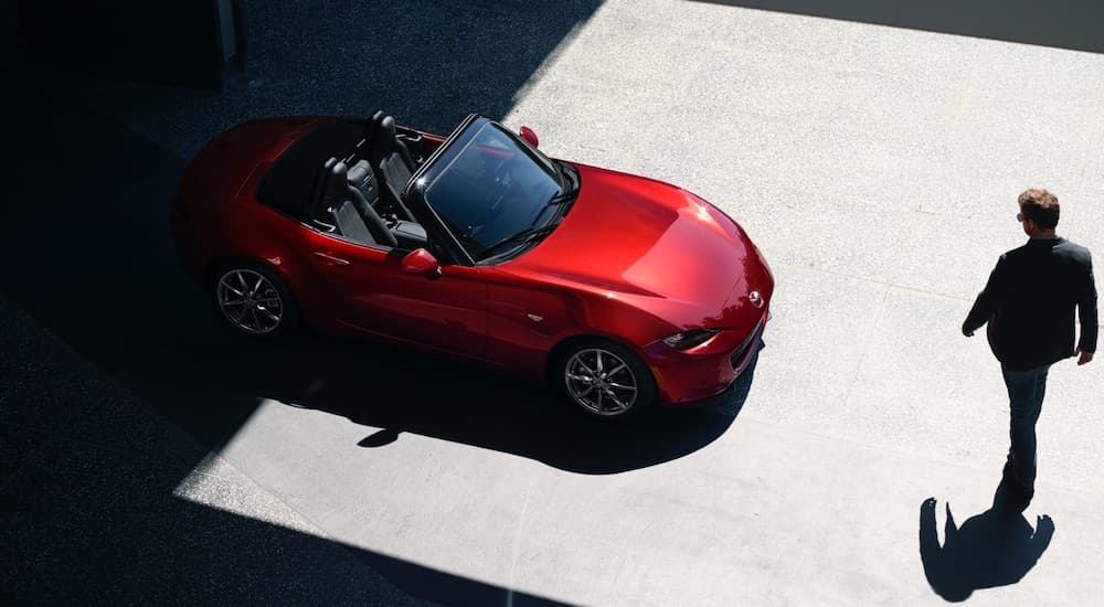 A red 2022 Mazda MX5 Miata is shown from a high angle with the driver approaching.