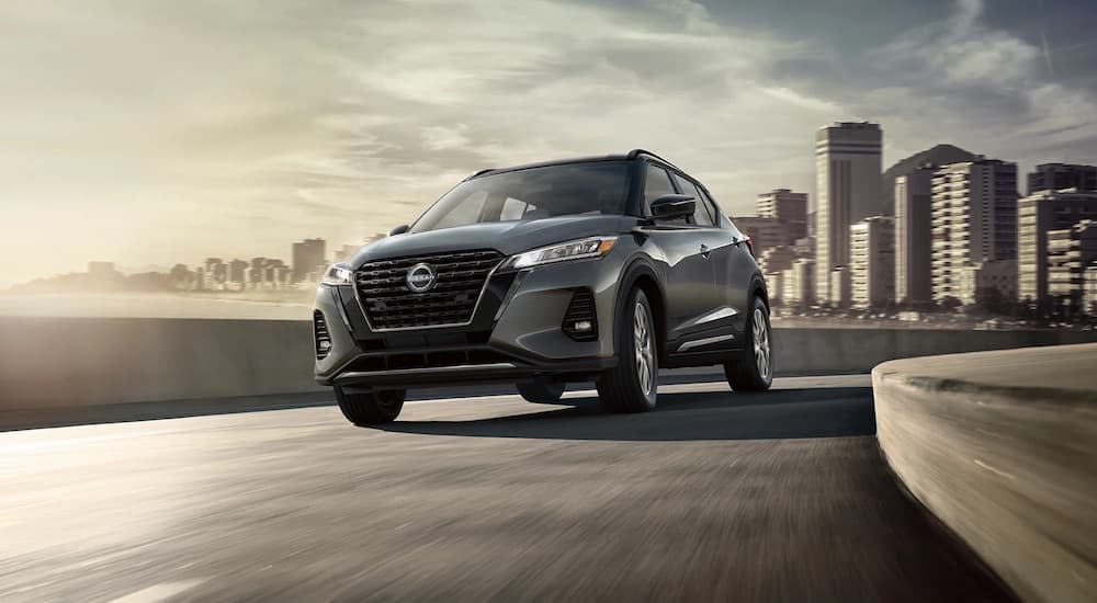 A grey 2022 Nissan Kicks is shown from the front while rounding an overpass.