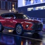 A red 2023 Chevy Blazer RS is shown from the front at an angle while it drives through a city at night.