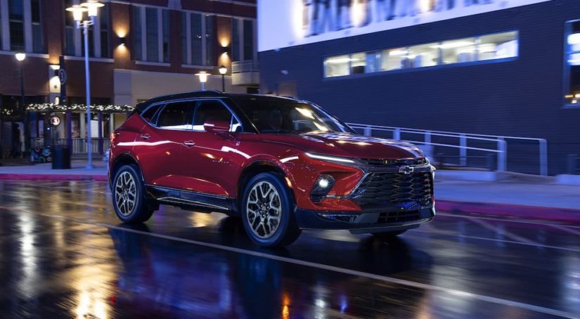 A red 2023 Chevy Blazer RS is shown from the front at an angle while it drives through a city at night.