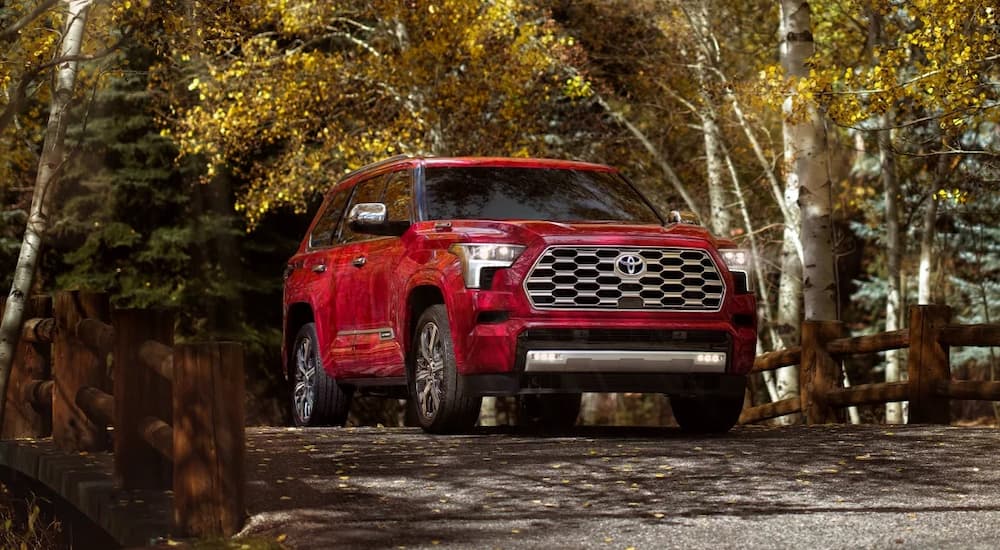 A red 2023 Toyota Sequoia is shown driving over a bridge.