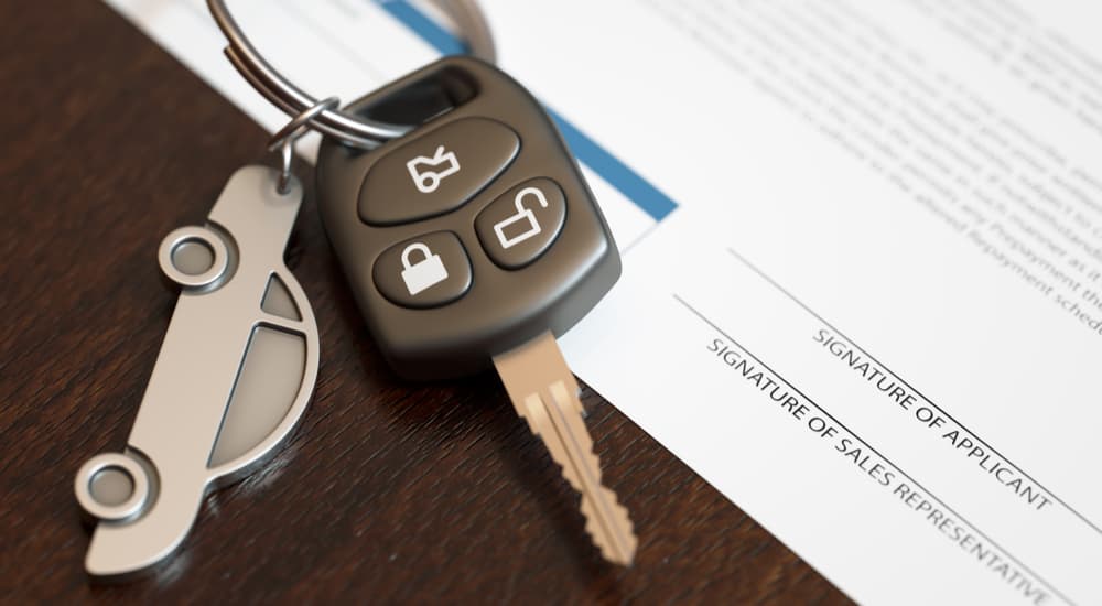 A car key and keychain are shown on car loan financing paperwork.