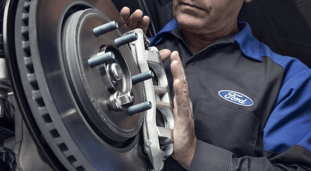 A Ford mechanic is shown inspecting a certified pre-owned vehicle's brakes.