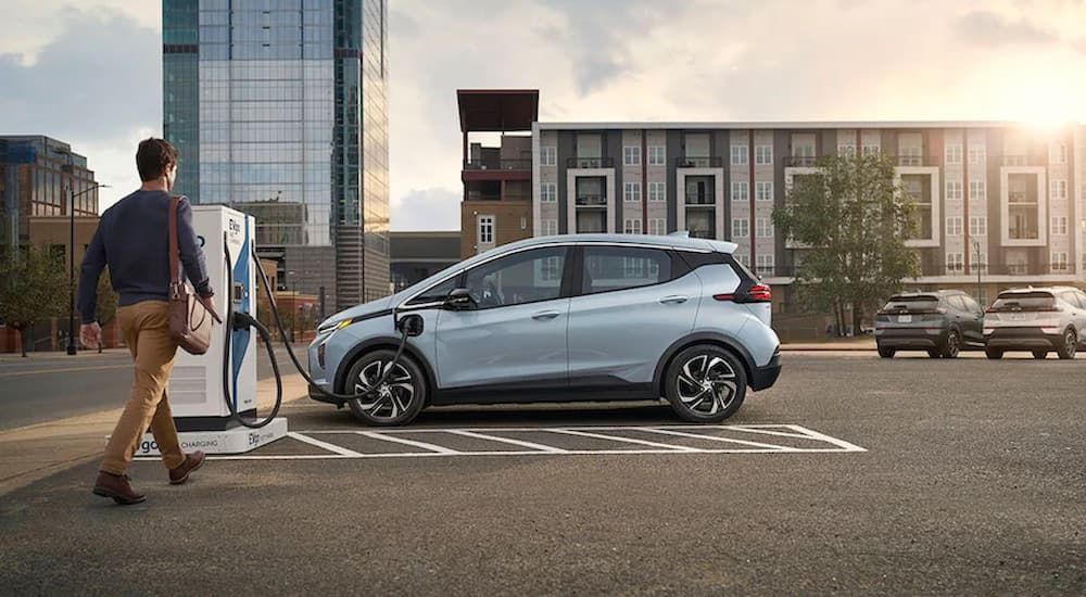 A light blue 2022 Chevy Bolt EV is shown parked at a public charging station.