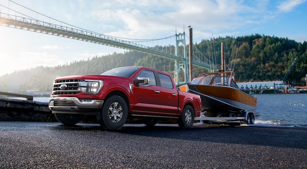 A red 2022 Ford F-150 Lariat is shown towing a boat out of a body of water.