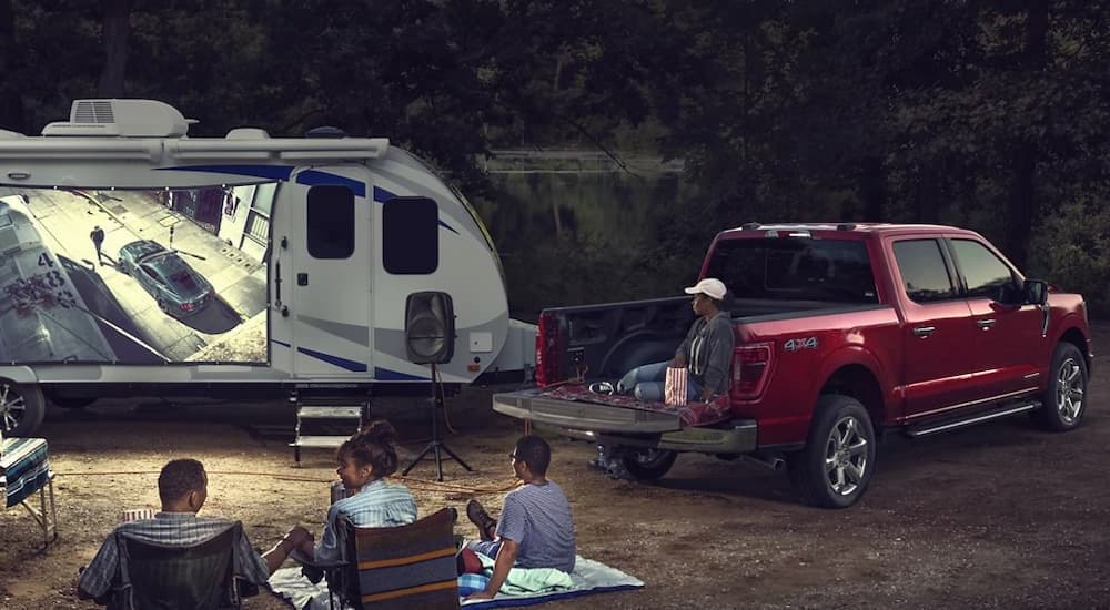 A red 2022 Ford F-150 is shown parked at a campsite after visiting a Ford truck dealer near you.