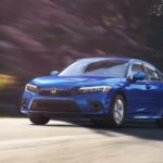 A blue 2022 Honda Civic is shown driving from the front at an angle after leaving a Honda dealer near you.