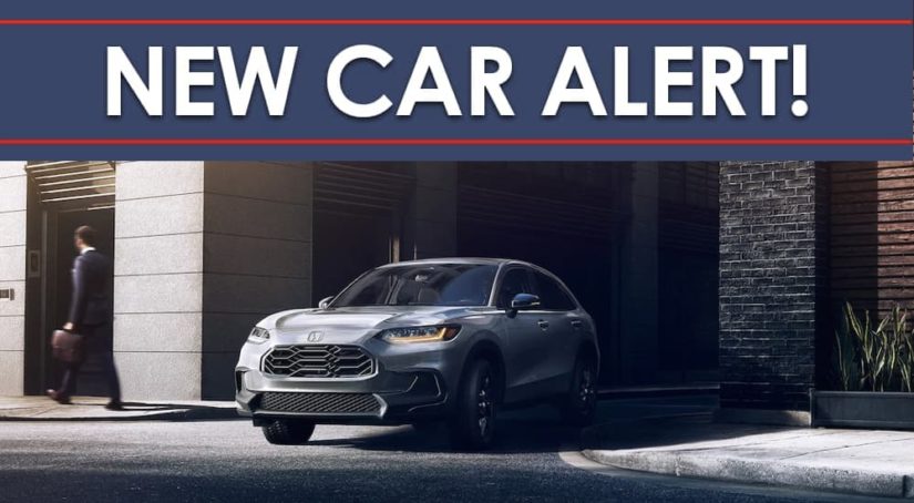 A grey 2023 Honda HR-V Sport is shown on a city street under a new car alert banner.