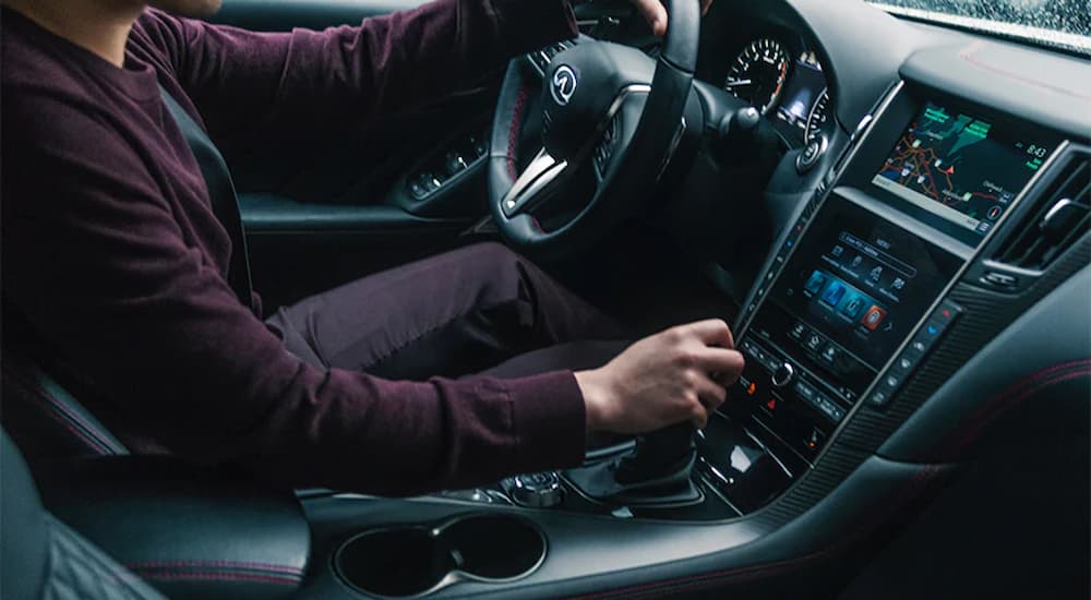 A man is shown driving a 2021 Infiniti Q50 with a black leather interior.