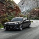 A black 2023 BMW 760i Xdrive is shown from the front while driving on a mountain road.