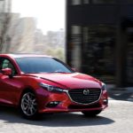 A red 2018 Mazda3 is shown leaving a used Mazda dealership.