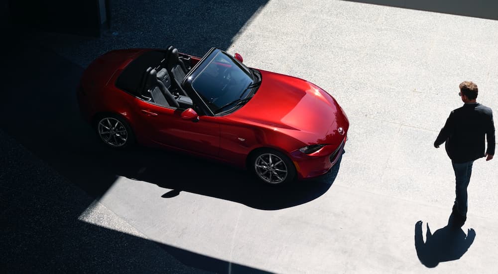 A red 2021 Mazda MX-5 Miata is shown from a high angle parked on concrete.