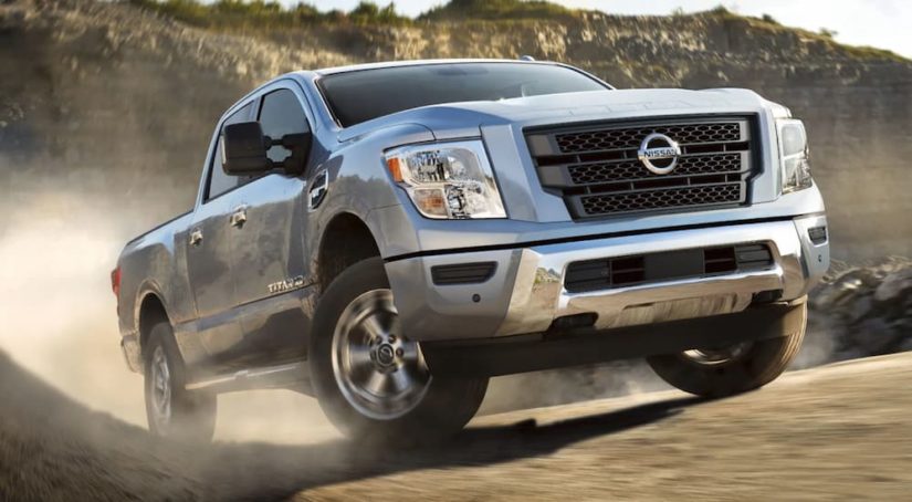 A silver 2021 Nissan Titan is shown off-roading after leaving a used Nissan truck dealer.