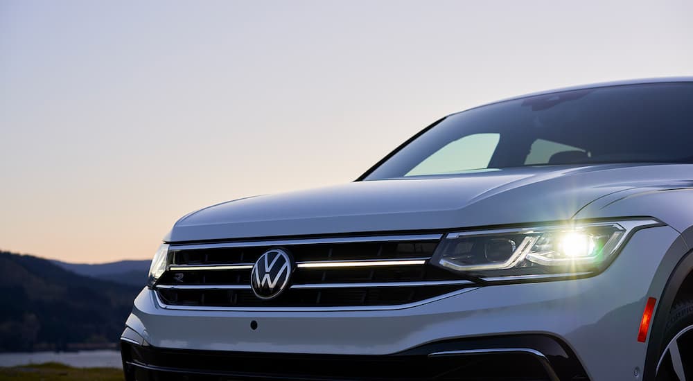 A close up of the hood and grille of a white 2022 Volkswagen Tiguan is shown during dusk.