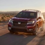 A red 2020 Honda Passport Elite is shown driving through a desert.
